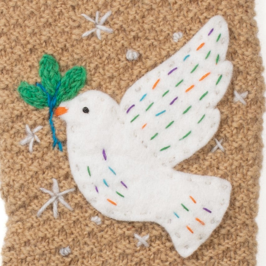 Close up of Handcrafted wool knit Christmas stocking with white dove with colorful embroidery. Handmade in Nepal, Fair Trade.