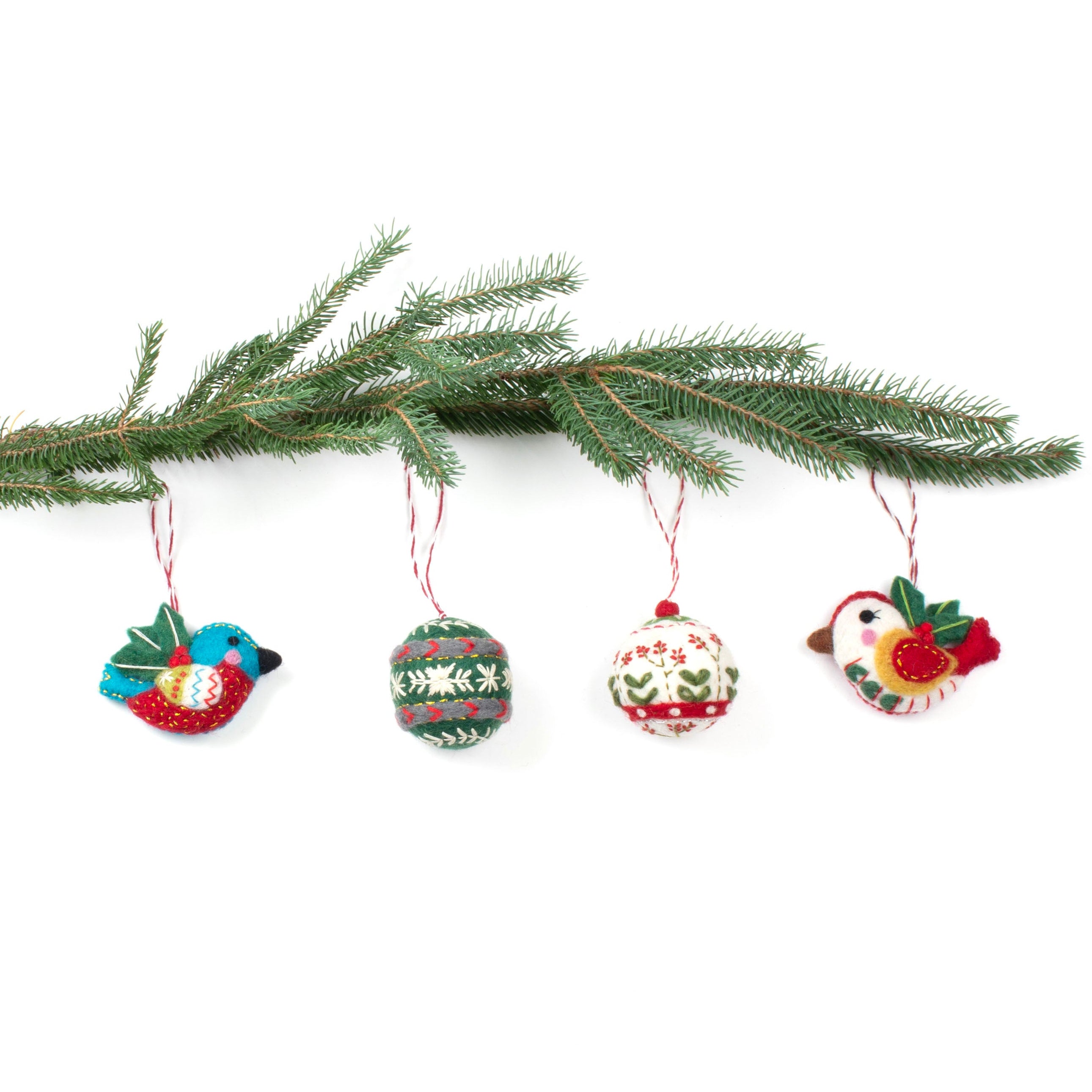 Set of four hand-felted wool Christmas ornaments featuring two colorful birds and two embroidered baubles hanging from a pine branch, handmade in Nepal.